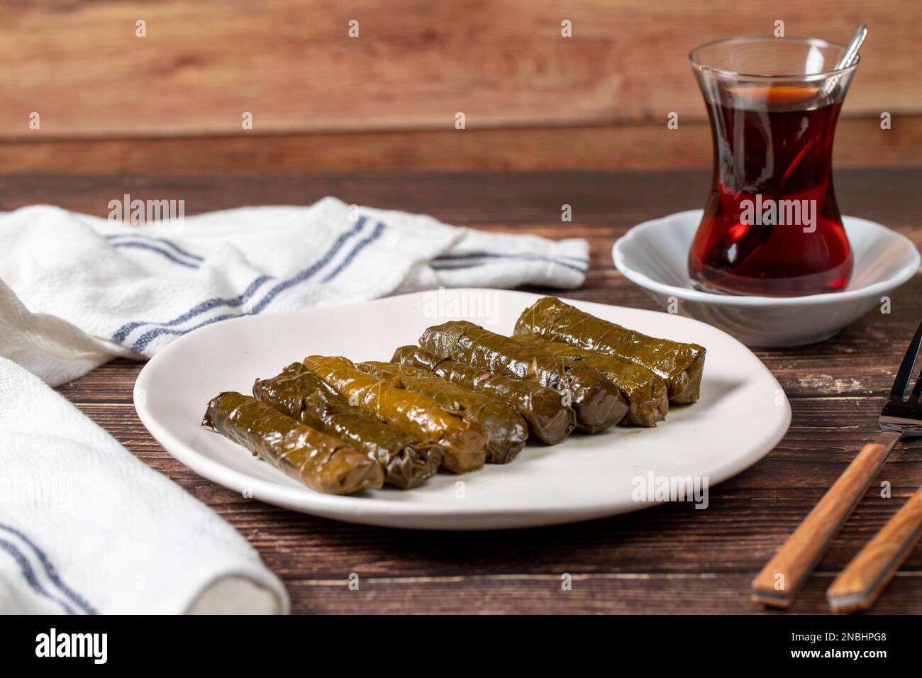 Farce délicieuse (yabrak sarma). Cuisine traditionnelle spécialités turques. Feuilles de raisin farcies de riz dans une assiette sur plancher de bois Banque D'Images