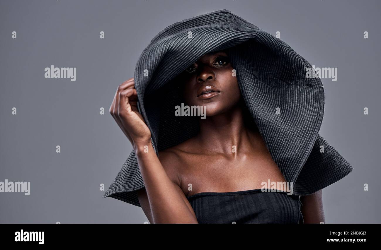 Je garde ma belle peau protégée du soleil. une jeune femme portant un grand chapeau de soleil sur fond gris. Banque D'Images