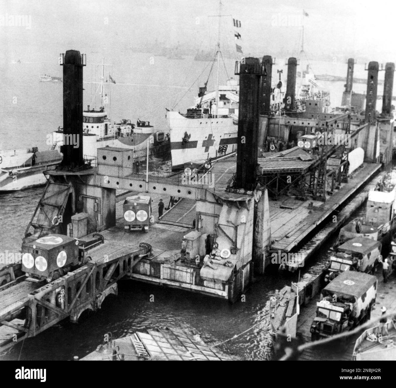Ambulances bring casualties to a hospital ship tied up at the LST pier head of the British prefabricated harbor off the Normandy coast on Oct. 21, 1944 while Army fire service vehicles are discharged from landing craft (tank) in right foreground. (AP Photo) Banque D'Images