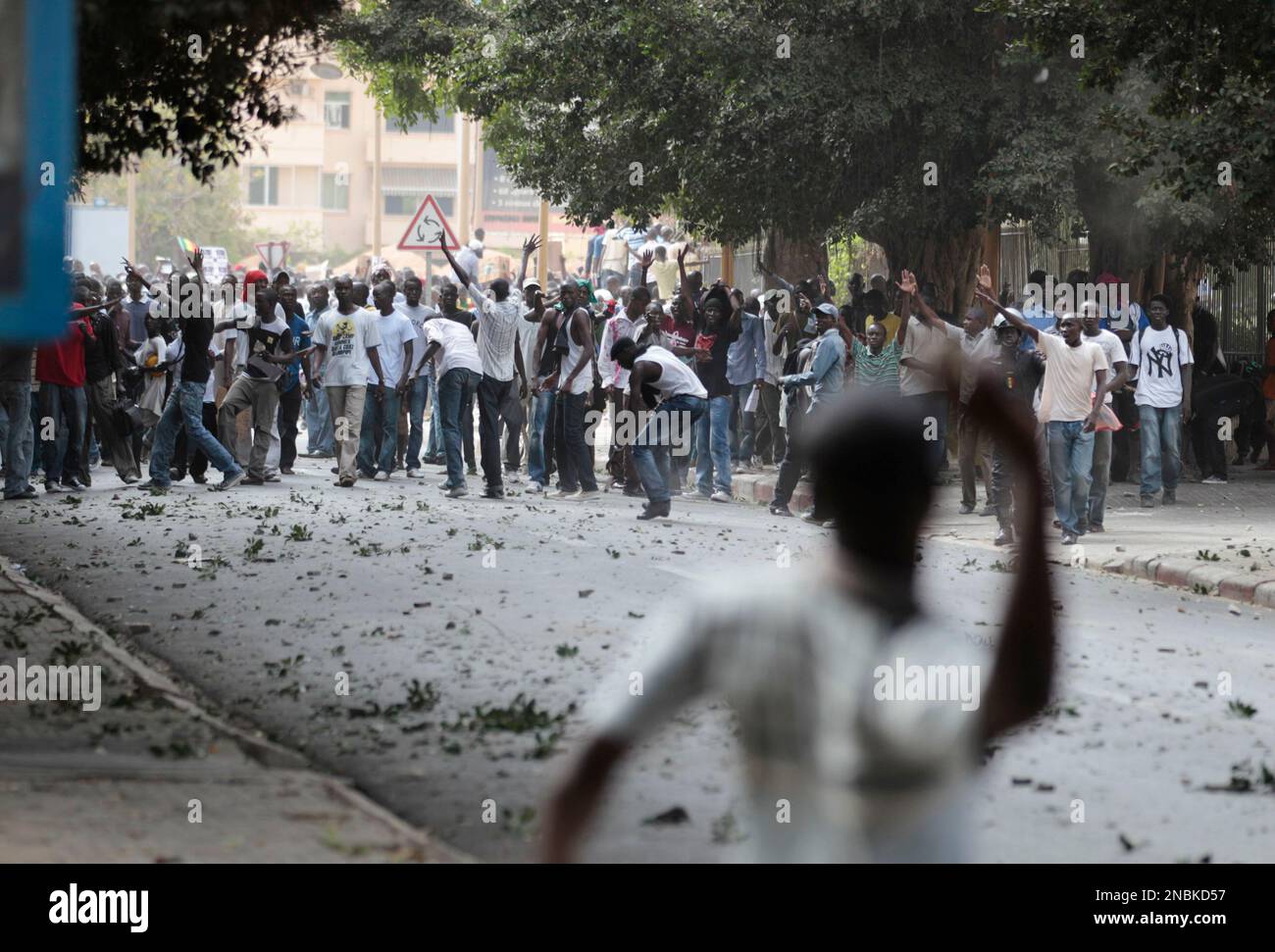 A supporter of President Abdoulaye Wade, foreground, throws rocks at demonstrators protesting proposed constitutional changes, outside the National Assembly in central Dakar, Senegal Thursday, June 23, 2011. Senegalese police lobbed tear gas at thousands of protesters who amassed in the capital Thursday to oppose proposed changes to the constitution that critics said would benefit the longtime president and his family. (AP Photo/Rebecca Blackwell) Banque D'Images