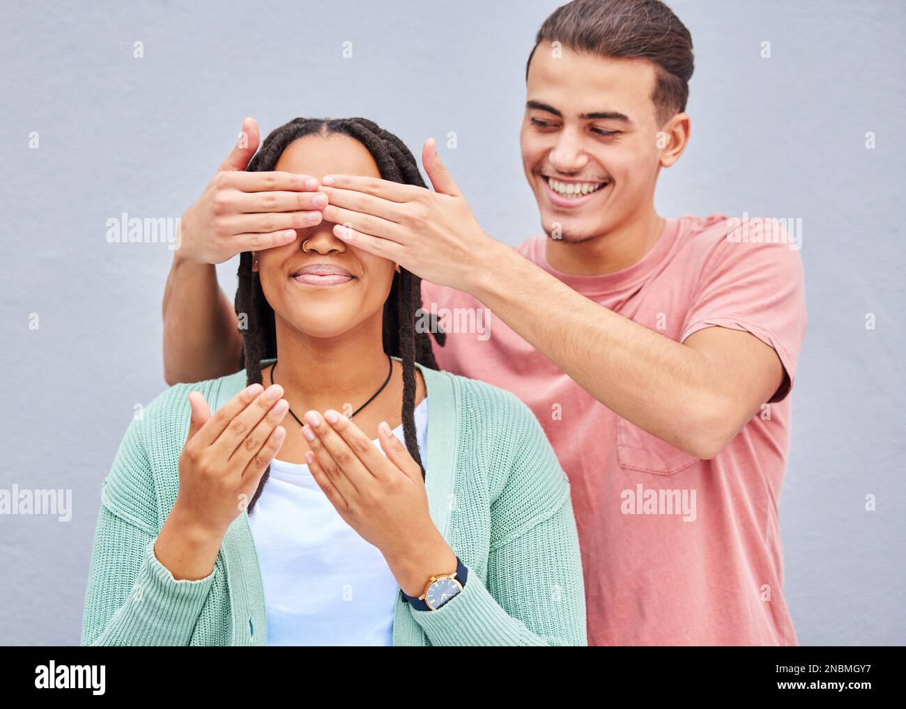 Wow, surprise ou mains et un couple sur un fond gris extérieur avec un homme couvrant les yeux de sa petite amie. Diversité, mains ou rencontres avec un Banque D'Images
