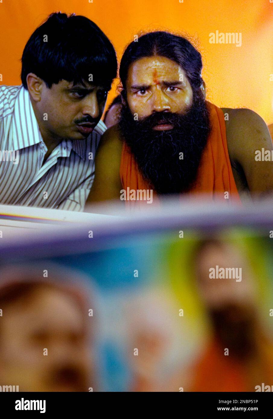 Renowned yoga guru Baba Ramdev, right, talks with one of his follower ...