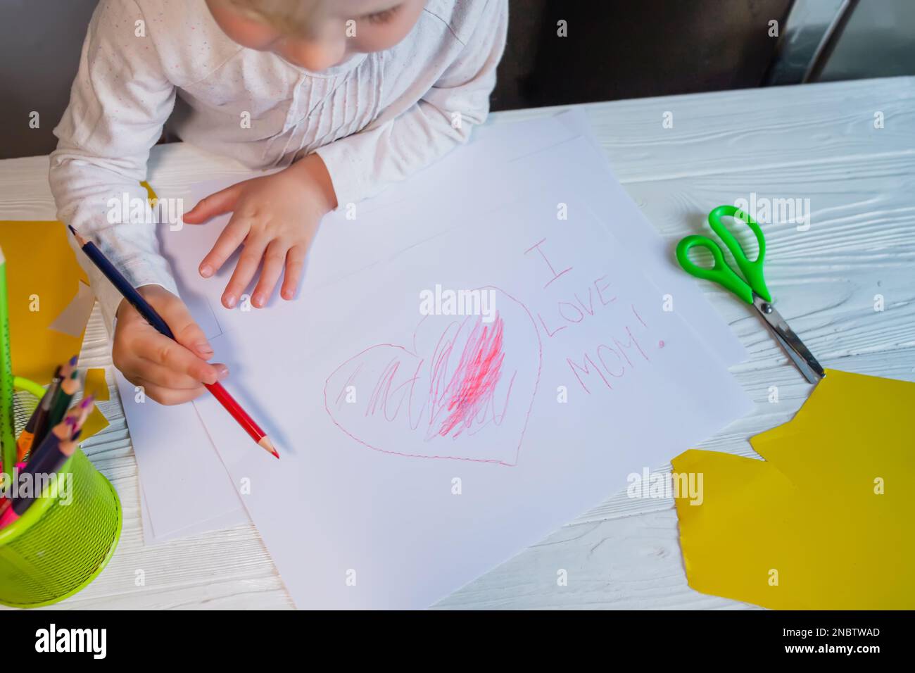 Carte de fête des mères. L'enfant a attiré un coeur et a écrit que j'aime ma mère. Banque D'Images
