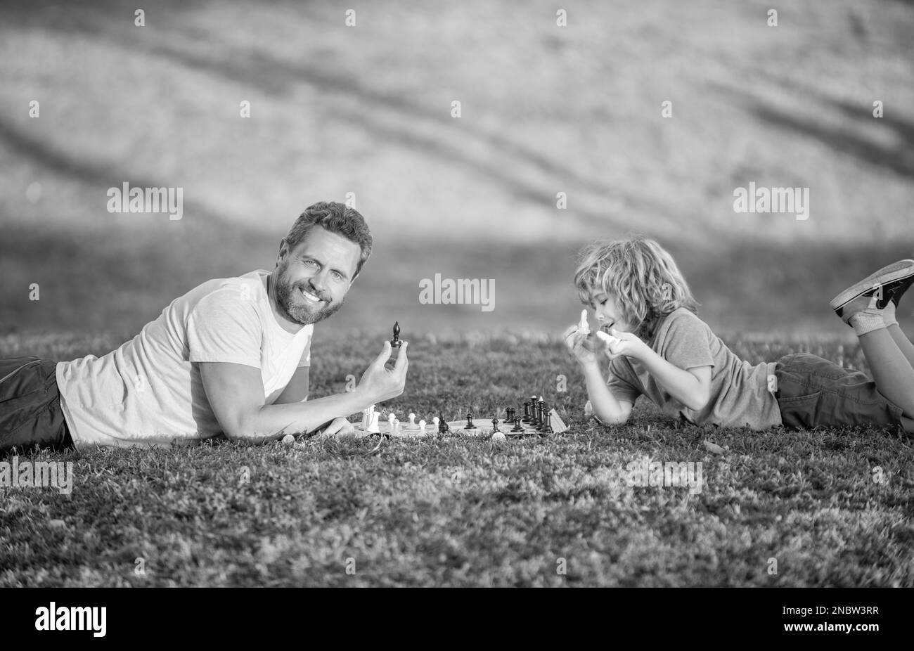 amitié. père et enfant jouent à la logique. père et fils jouant aux échecs sur l'herbe dans le parc. Banque D'Images
