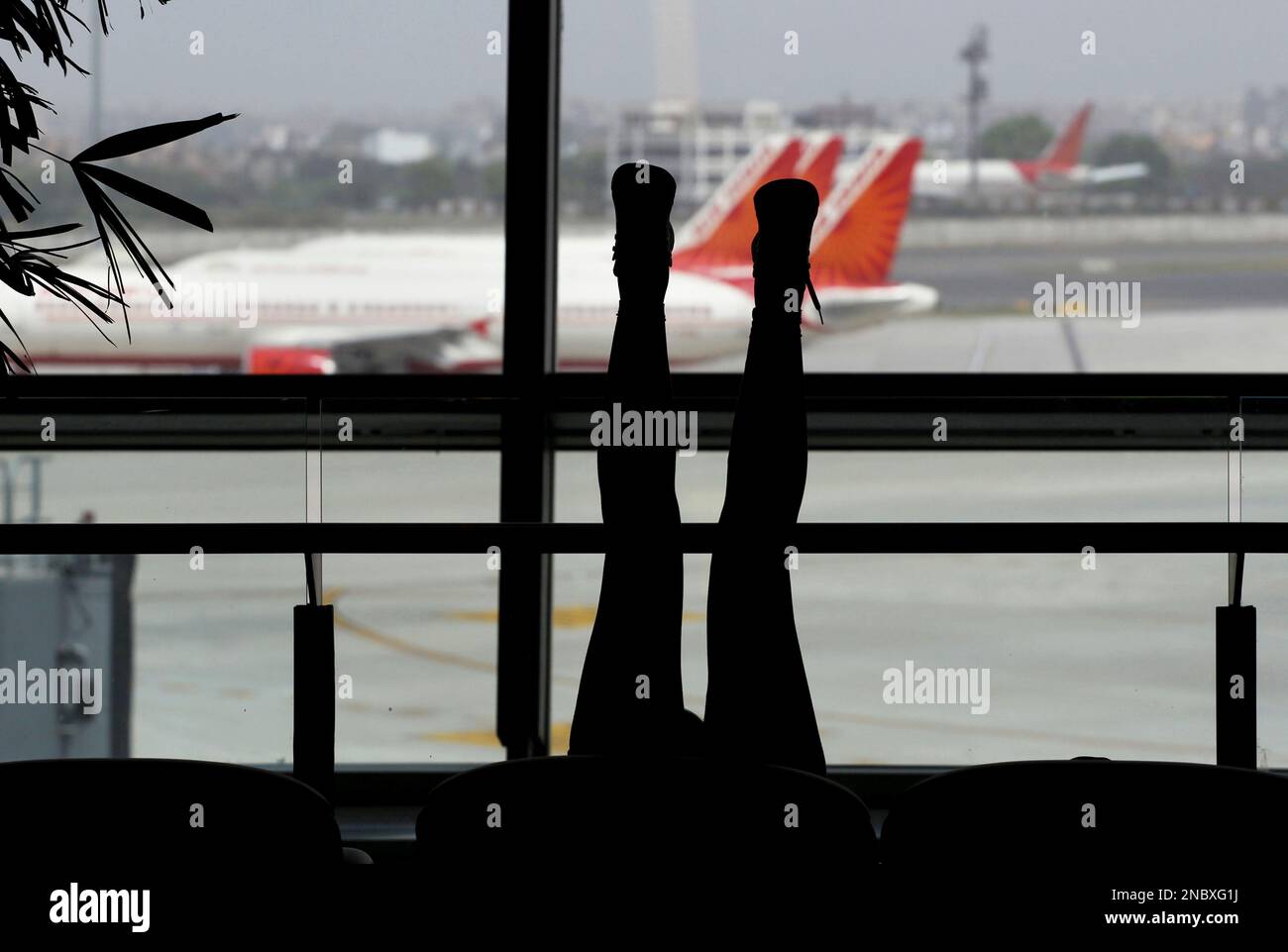 A waiting traveler stretches her legs as passenger jets from Air India, India's national carrier, that were meant to be flying international routes sit idle at gates, at Indira Gandhi International Airport in New Delhi, India, Friday, April 29, 2011. The strike by one of the carriers pilots' union entered the third day leading to cancellation of dozens of flights including several international ones, according to local news reports. (AP Photo/Kevin Frayer) Banque D'Images