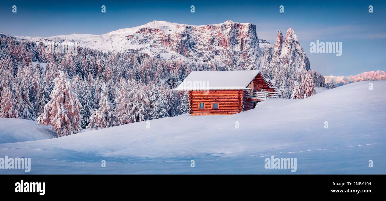 Vue panoramique le matin sur le village d''Alpe di Siusi avec chalet en bois. Magnifique lever de soleil d'hiver dans les Alpes Dolomites avec les pics de Santner et d'Euringer à l'arrière Banque D'Images