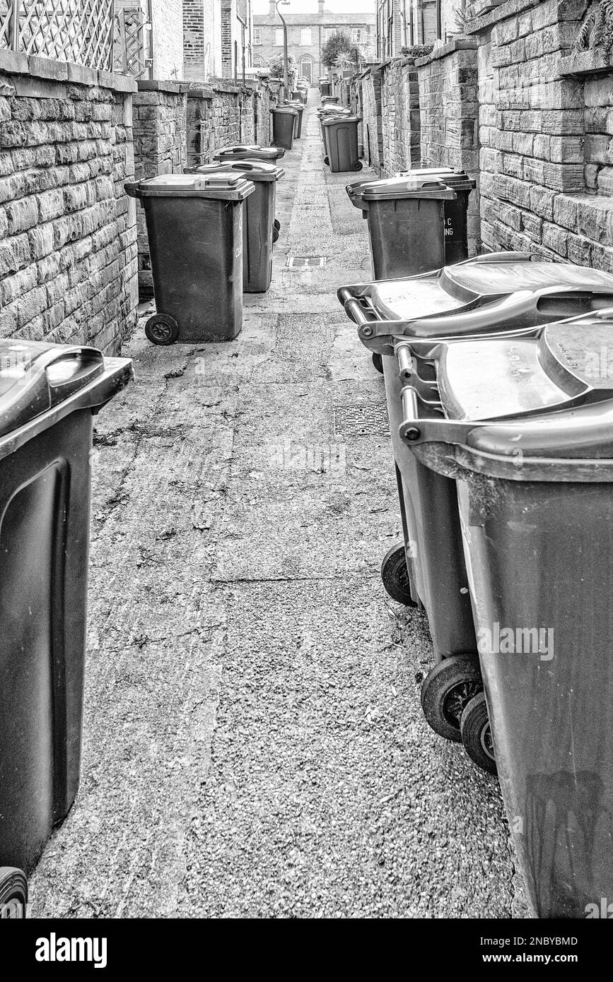 Les allées étroites entre les logements en terrasse dans la ville de Saltaire, dans le West Yorkshire, où les bennes à roues prolifèrent et occupent de l'espace Banque D'Images