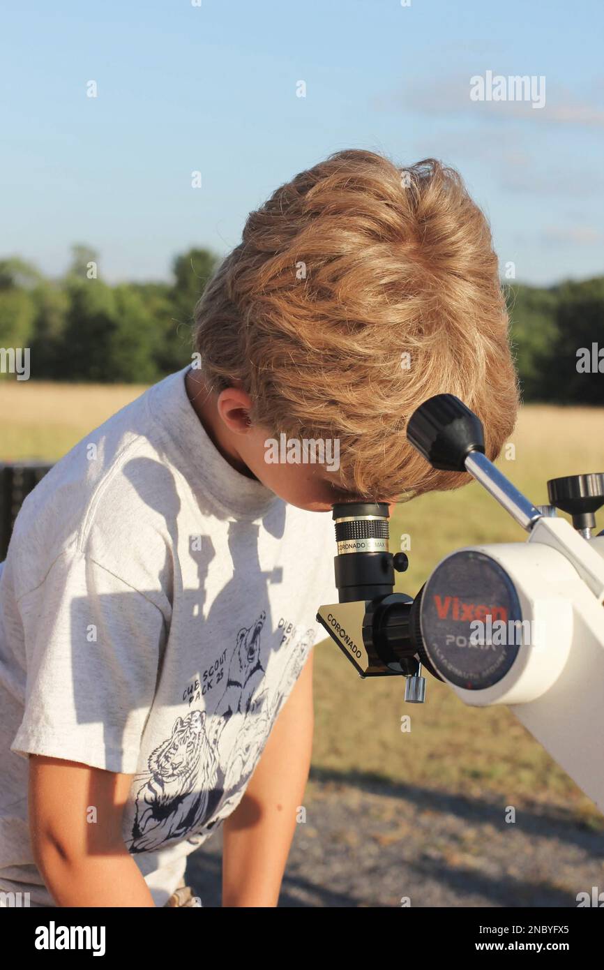 Un garçon regarde à travers un grand télescope pour l'observation solaire avant que la fête d'observation des étoiles se produise au parc régional de Cherry Springs en Pennsylvanie Banque D'Images