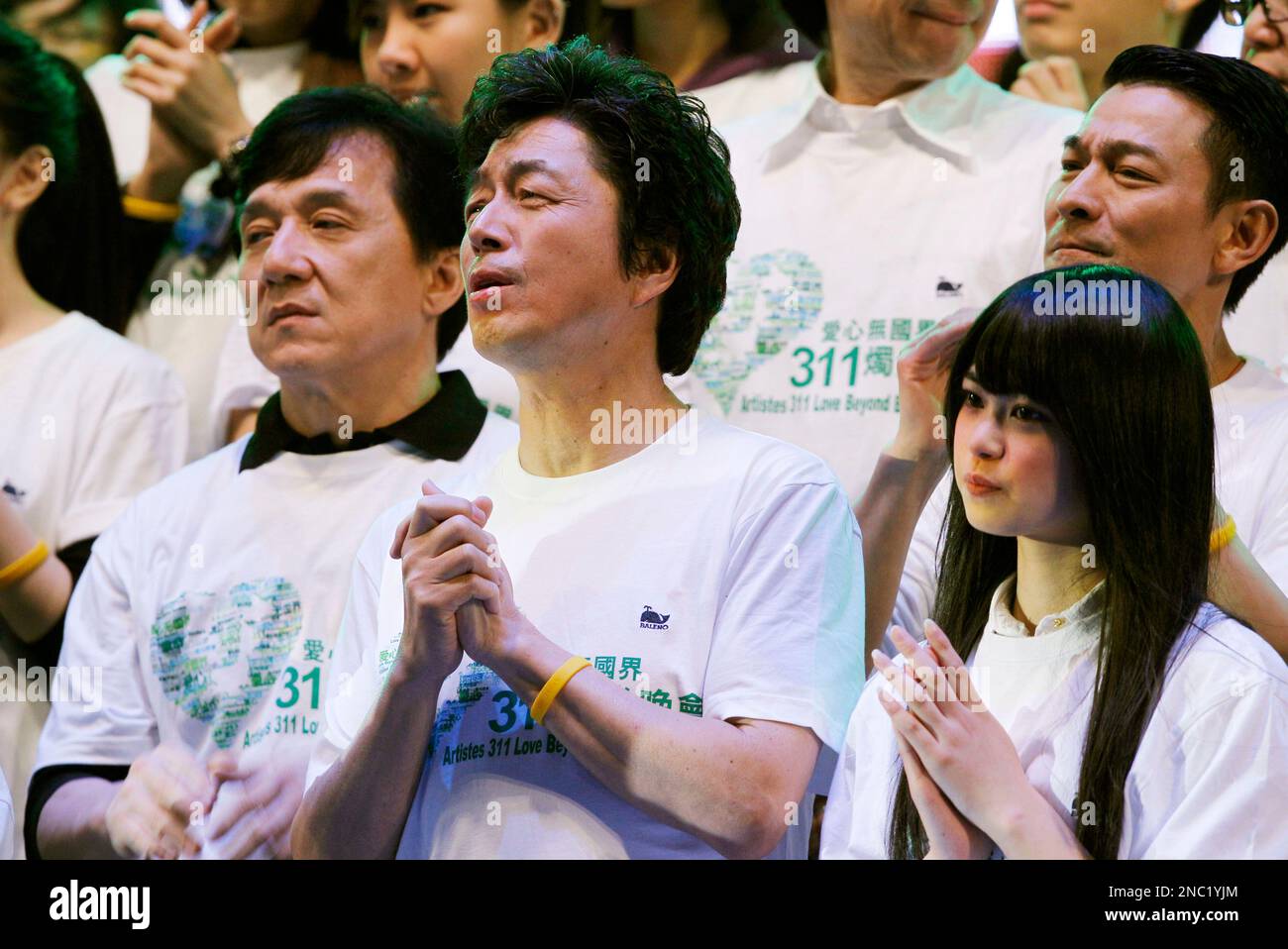 Hong Kong movie star Jackie Chan, left, and Japanese singer Masatoshi Nakamura, center, take part in the charity concert "Artistes 311 Love Beyond Borders" in Hong Kong Friday, April 1, 2011. Hong Kong entertainment industry staged the charity concert to raise funds for victims of Japan's massive earthquake and tsunami. (AP Photo/Kin Cheung) Banque D'Images