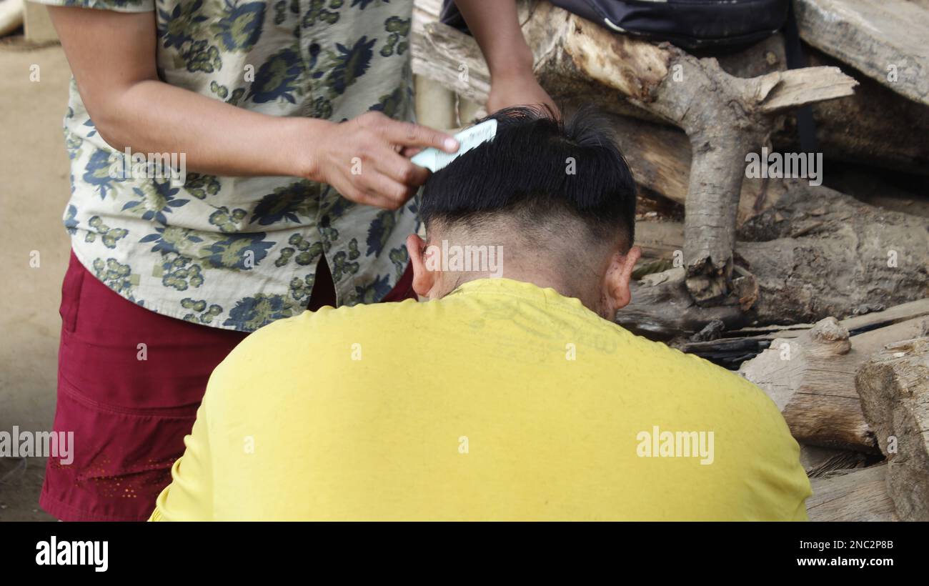 Un petit homme s'assoit dans un coiffeur au styliste, un enfant d'école se coupe les cheveux dans un salon de beauté, un homme dans un salon de coiffure local, un homme court Banque D'Images