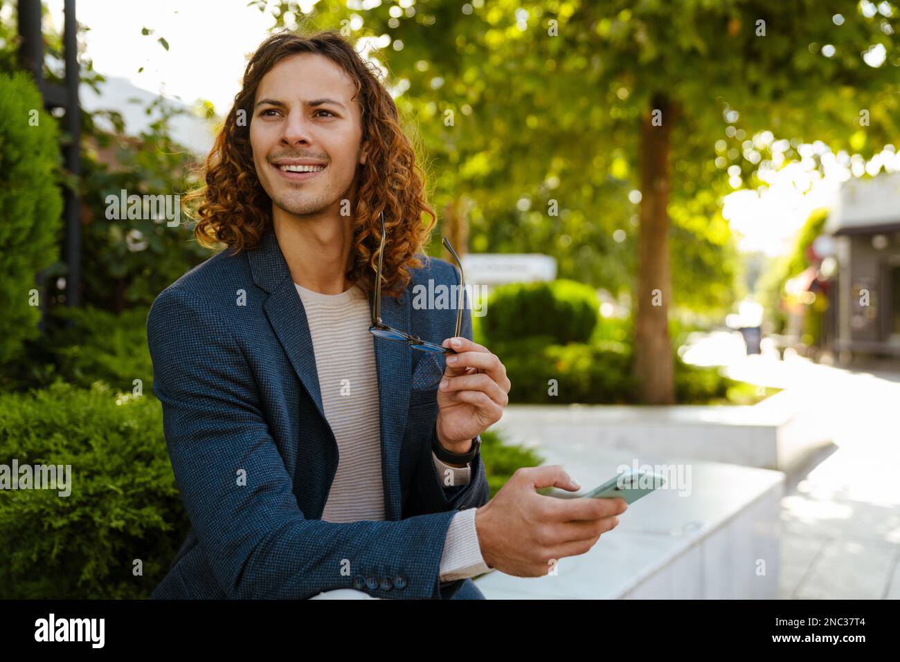 Ginger homme européen parlant sur téléphone mobile tout en étant assis dans le parc d'été Banque D'Images