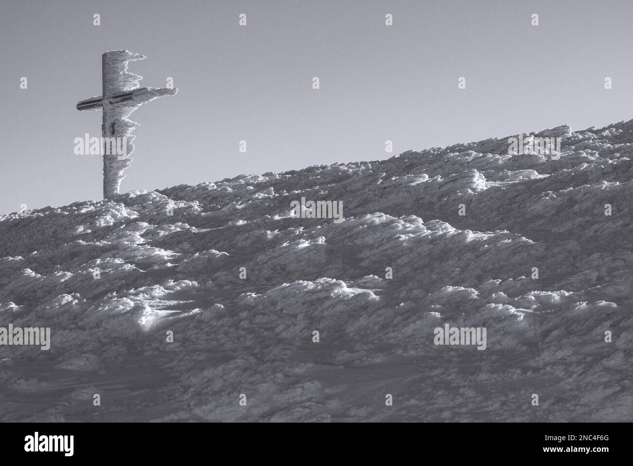 Photo en noir et blanc d'une croix d'hiver couverte de neige, l'oeuvre du vent dans les montagnes carpathes Banque D'Images