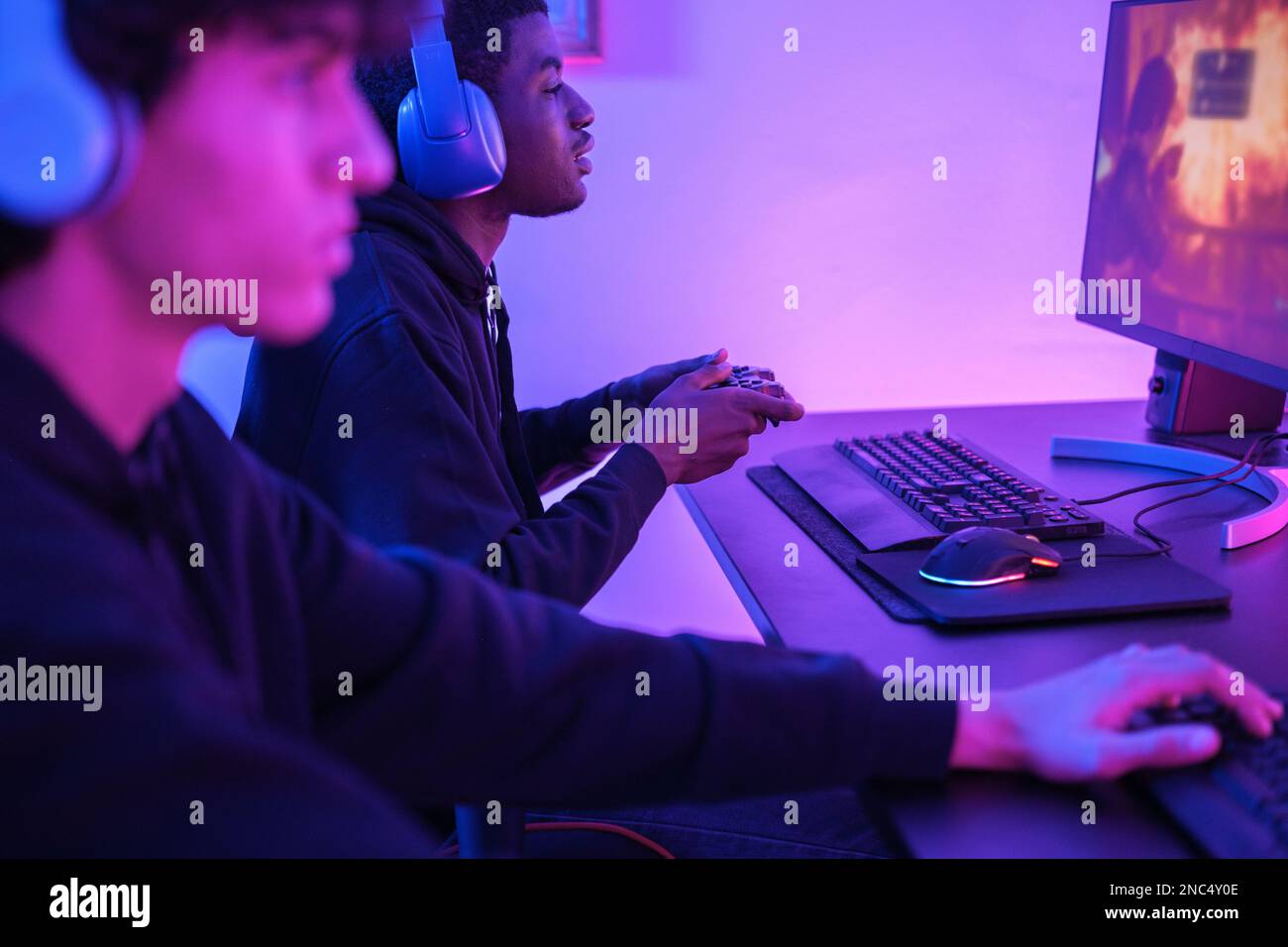 Deux jeunes amis jouant ensemble à des jeux vidéo. Concentrez-vous sur le type en arrière-plan. Concept: En ligne, jeux vidéo, technologie Banque D'Images