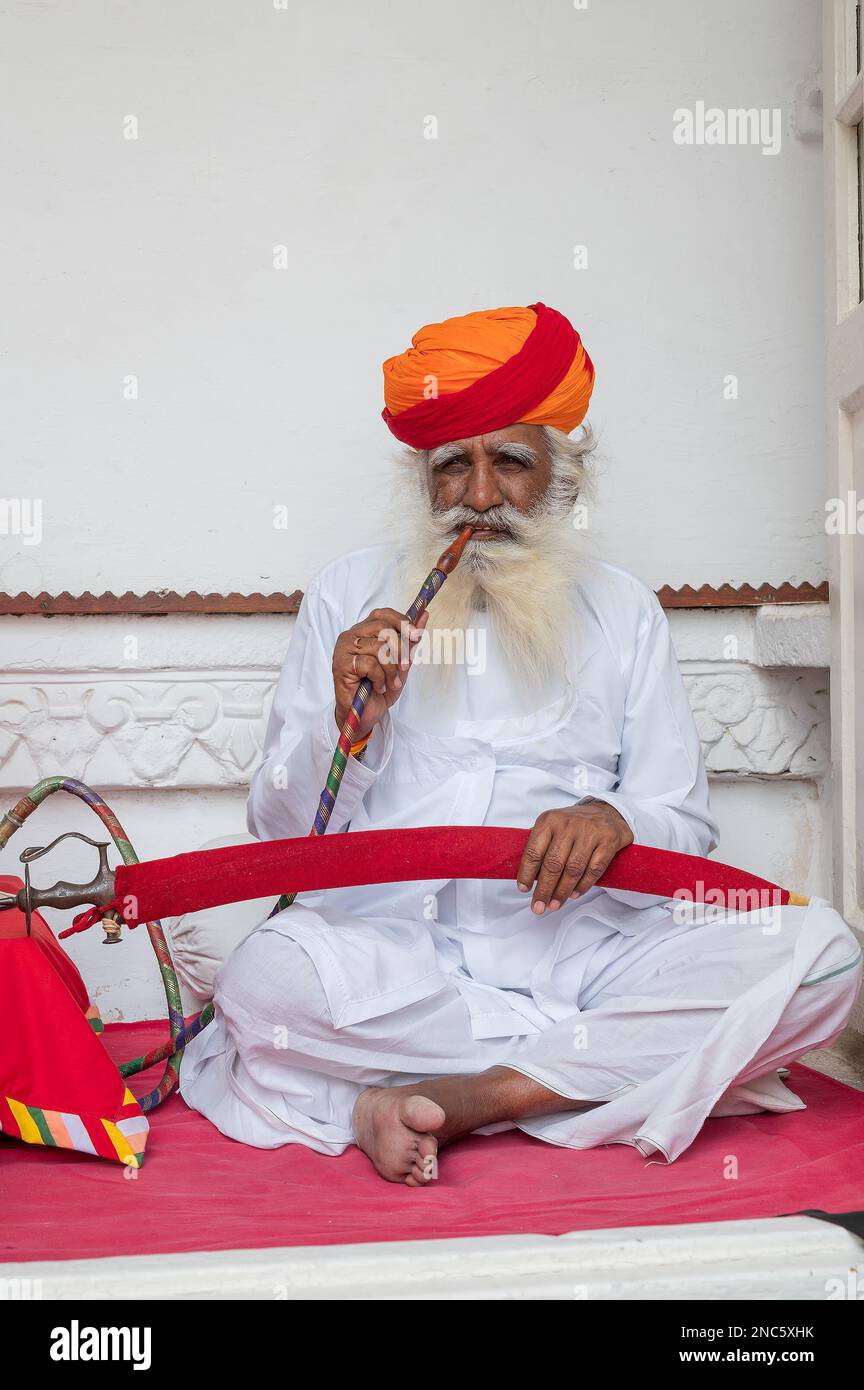 Jodhpur,Rajasthan,Inde - 19th octobre 2019: Rajput homme âgé fumer par un nargua, portant Marathi pagri et épée sur les genoux. Le narguilé est un menumen Banque D'Images