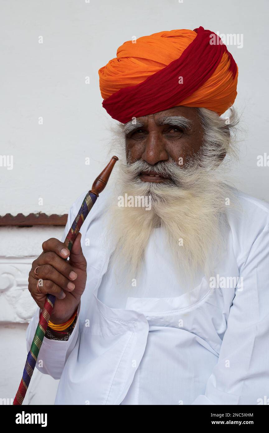 Jodhpur, Rajasthan, Inde - 19 octobre 2019 : Rajput homme âgé fumant à travers un narguilé, portant Marathi pagri. Le narguilé est un instrument de chauffage. Banque D'Images