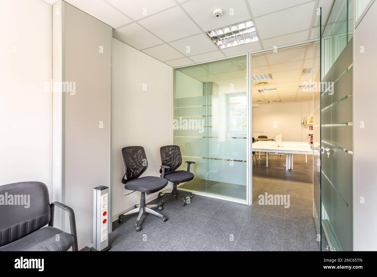 Bâtiment abandonné d'un propriétaire insolvable avec un intérieur dans un style de bureau simple. Bureaux, à gauche et à droite, avec des cloisons en verre et un petit soleil Banque D'Images