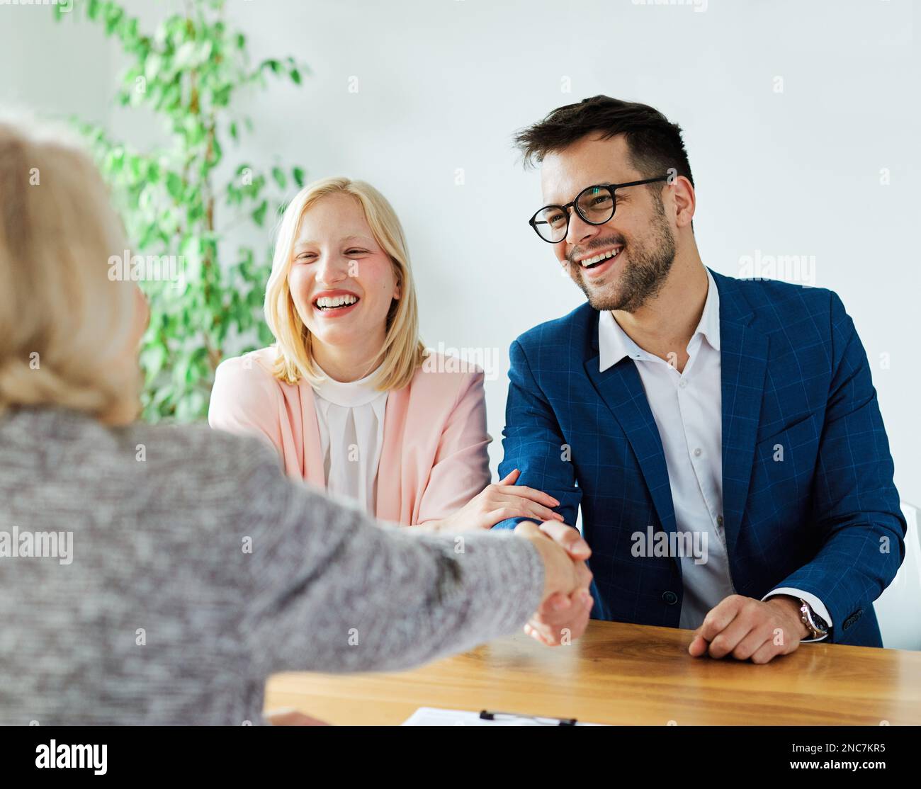 un jeune couple qui tremble les mains traite contrat d'investissement immobilier agent d'accord d'affaires poignée de main signature Banque D'Images