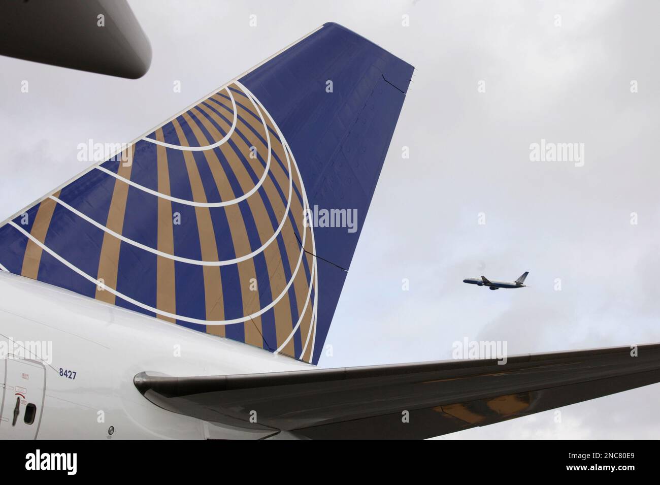 A United Airlines plane flies over the tail of a United Airlines 747-400, the first Boeing 747 entering service in the new United livery, at San Francisco International Airport in San Francisco, Wednesday, Feb. 23, 2011. With the recent addition of the 747-400, at least one plane in each United mainline fleet has been painted in the new livery following the merger with Continental Airlines in October of last year. (AP Photo/Eric Risberg) Banque D'Images