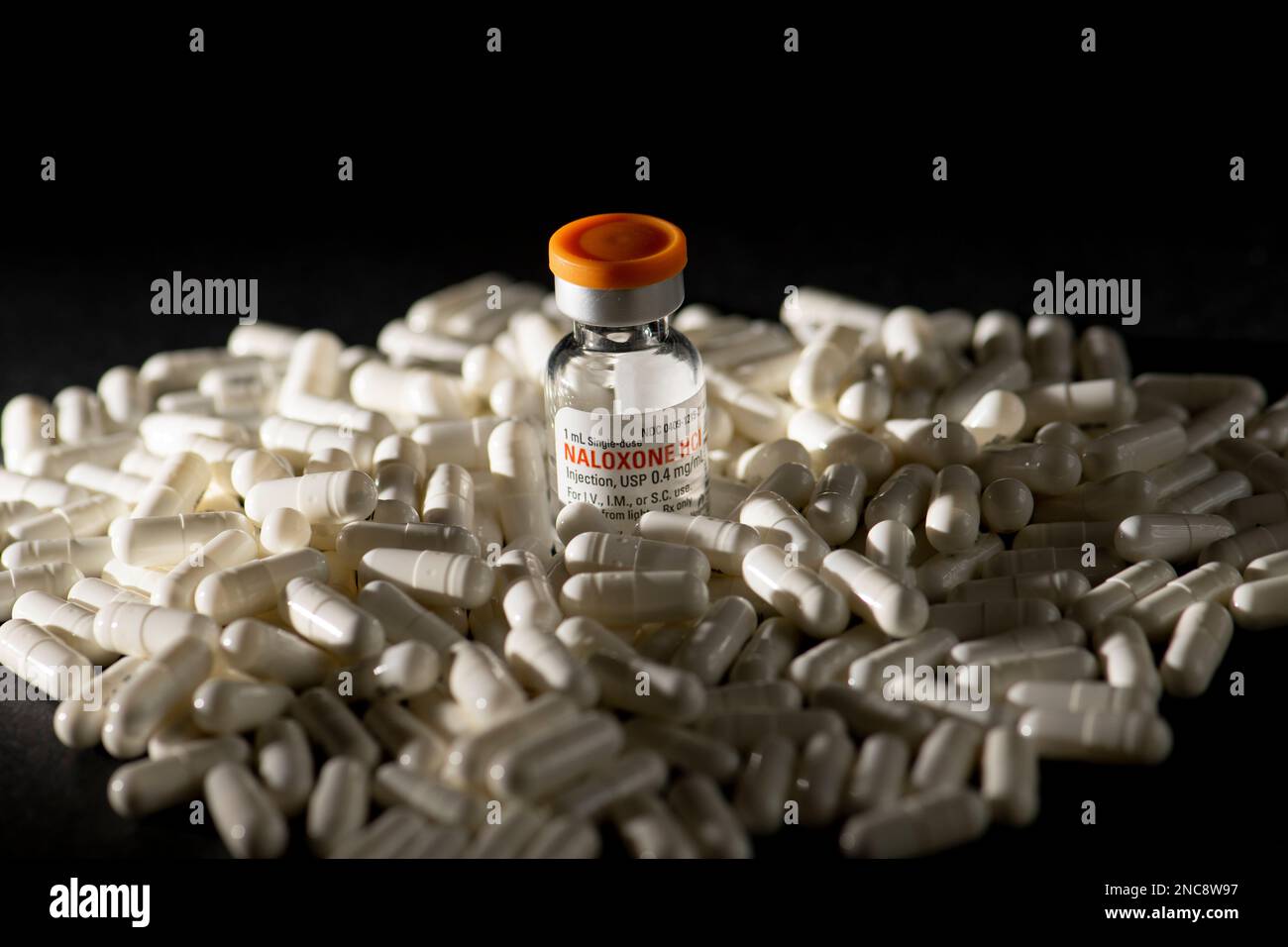 Une bouteille de naloxone sur un tas de pilules sur fond noir. La naloxone est un médicament qui sauve la vie qui peut inverser un surdosage d'opioïdes. Banque D'Images