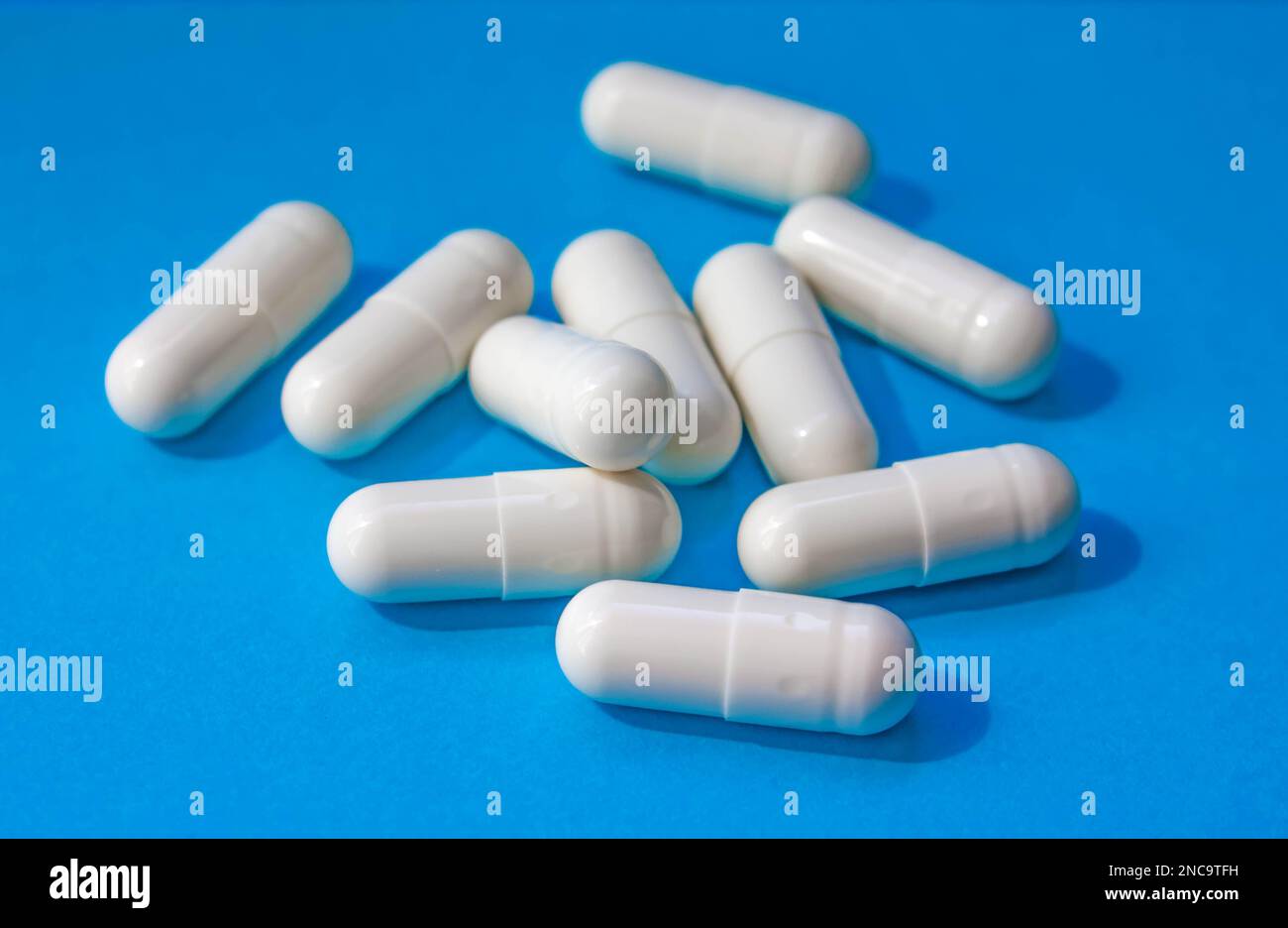 Pilules blanches dispersées sur fond bleu. Le concept de médecine, de pharmacie et de soins de santé. Pour les offres spéciales comme la publicité ou d'autres idées. Banque D'Images