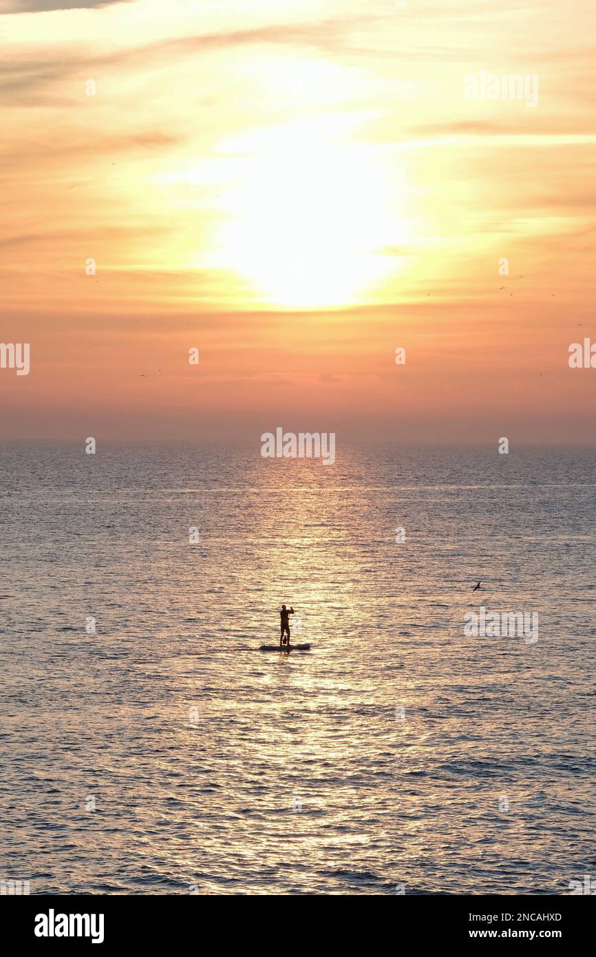 Brighton, Royaume-Uni. 14th février 2023. Un pédalo passe le long d'un ciel au coucher du soleil. Une journée sèche et lumineuse se termine par un coucher de soleil coloré assisté par des particules de poussière sahariennes provenant d'Afrique du Nord. Des températures plus douces que tardives sont attendues pour le reste de la semaine. Crédit : onzième heure Photographie/Alamy Live News Banque D'Images