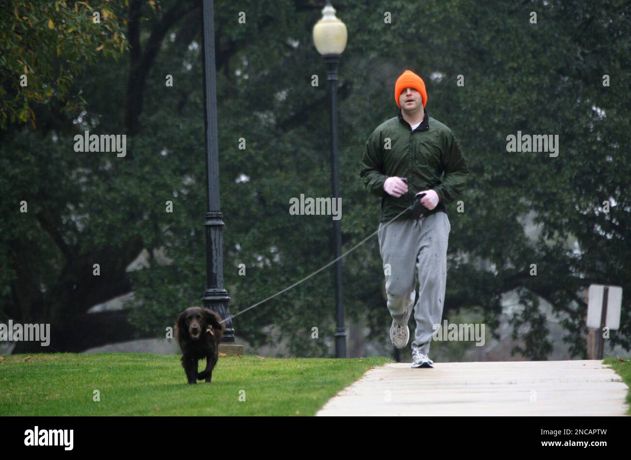 Tim Alford and his dog Dean run amid the ice and freezing weather in Jackson, Miss. A freezing winter storm that coated roads and bridges with ice is blamed in the deaths of at least three people in Mississippi, but conditions were expected to improve Friday as temperatures inched above freezing. The Mississippi Department on Transportation reported ice on bridges and roads Friday morning in more than half of Mississippi's 82 counties. (AP Photo/Rogelio V. Solis) Banque D'Images