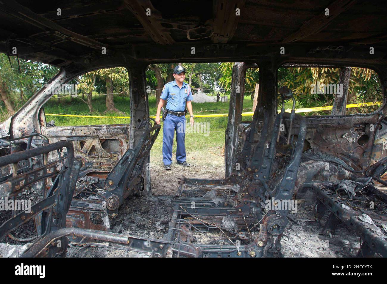 A Philippine National Police officer looks at the burnt remains of an SUV allegedly owned by slain car dealer Emerson Lozano Wednesday Jan. 19, 2011 at a remote village of San Simon, Dinalupihan township, Bataan province, about 150 kilometers (93 miles) northwest of Manila, Philippines. Police are puzzled by the gangland-style killings of Lozano and another car dealer, who were separately shot in the head then burned in attacks that shocked many in this already crime-weary country. Lozano is the son of Oliver Lozano, the lawyer of former Philippine strongman Ferdinand Marcos. (AP Photo/Bullit Banque D'Images