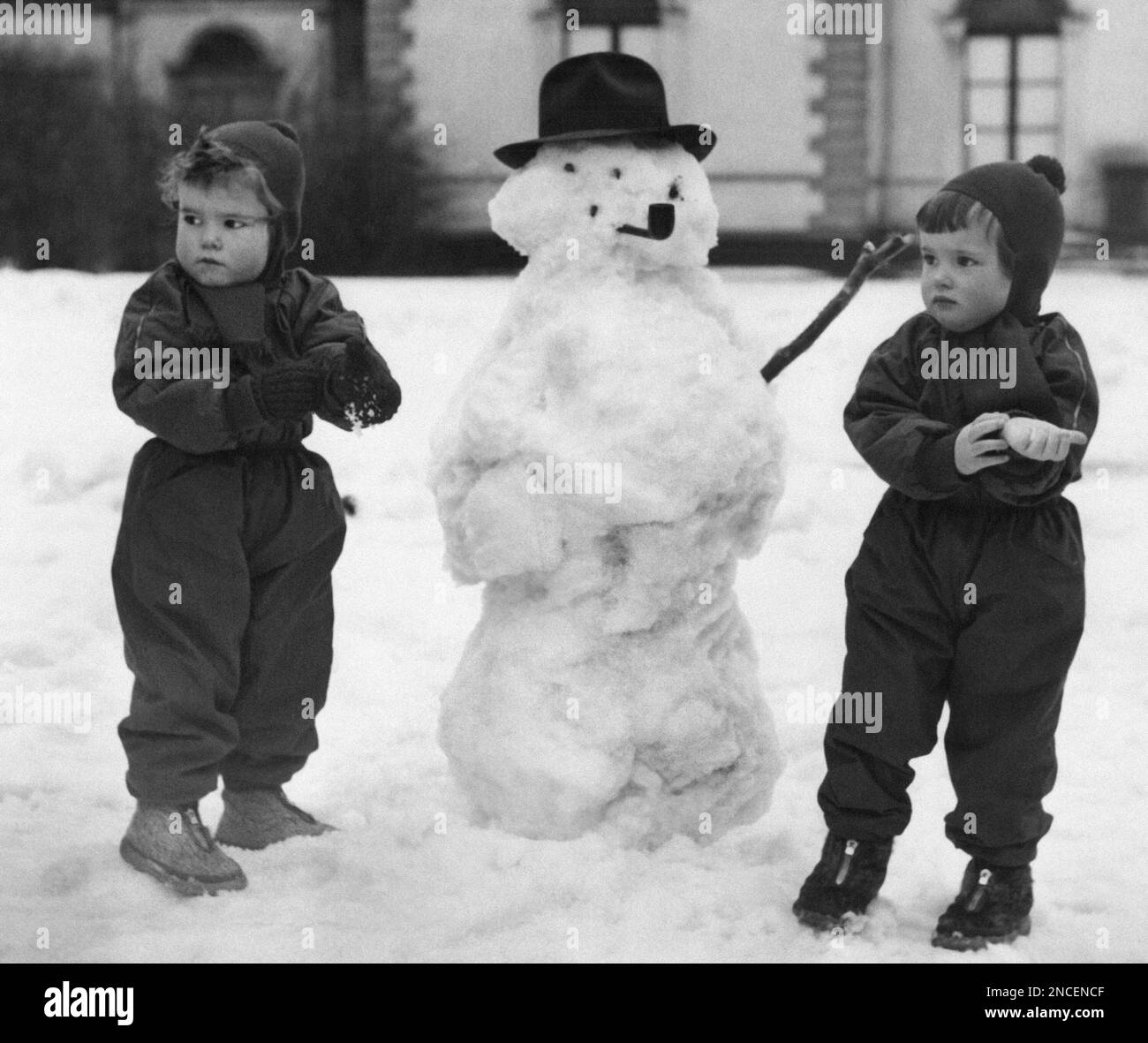 The twin children of actress Ingrid Bergman and her director-husband Roberto Rossellini, have fun with a snowman in Stockholm on Jan. 26, 1955. Ingrid and Isabella, together with their brother Robertino, had their snow fun at the Rosendahl Palace on the “Djurgarden”, which is a big park in Stockholm. Ingrid Bergman is in Stockholm to play “Joan of Arc.” (AP Photo) Banque D'Images