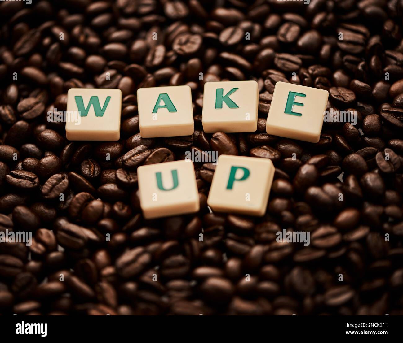 La vie commence après le café. Gros plan de lettres en bloc formant les mots se réveiller sur une pile de grains de café. Banque D'Images