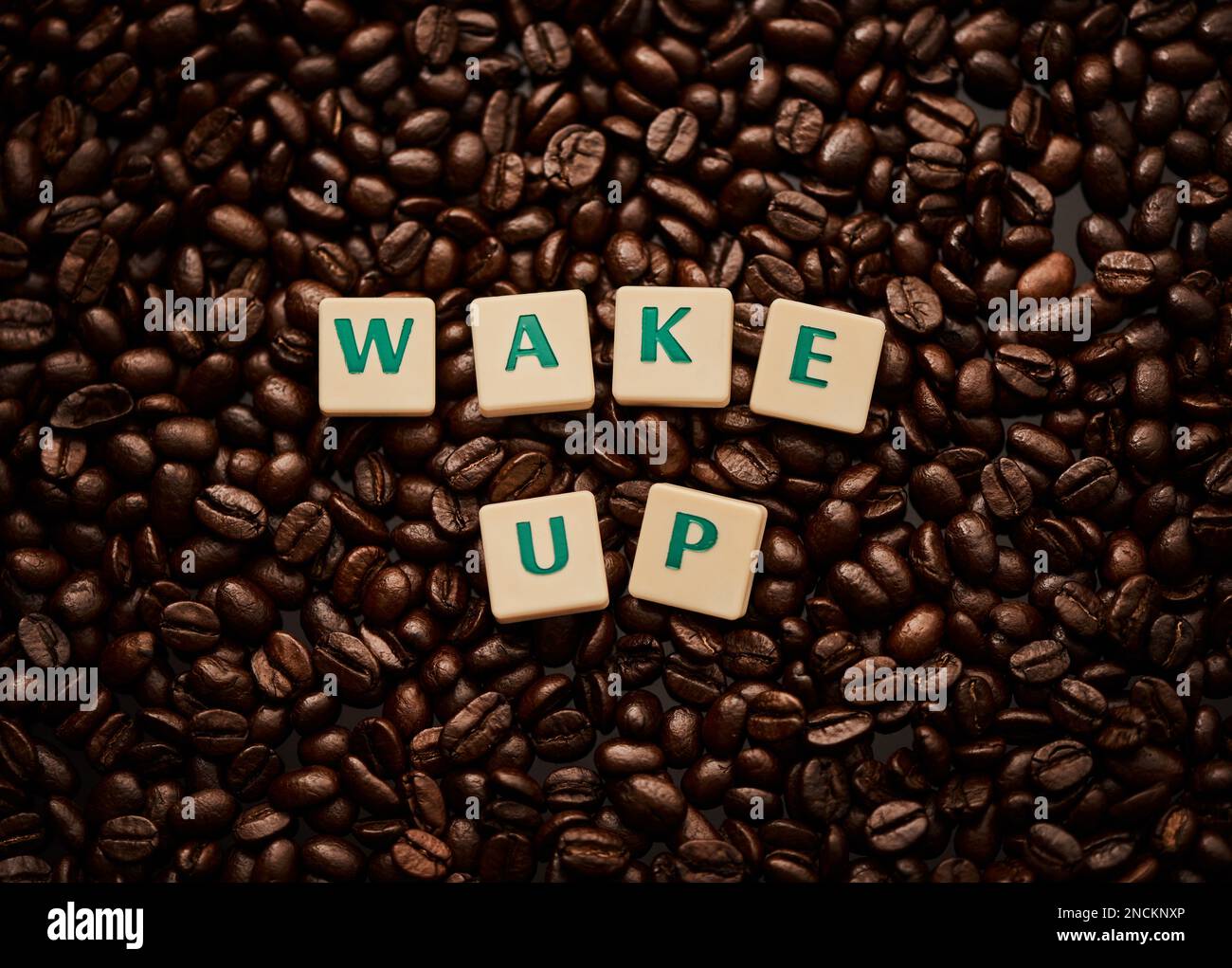 Éveillez votre âme avec l'arôme du café. Gros plan de lettres en bloc formant les mots se réveiller sur une pile de grains de café. Banque D'Images