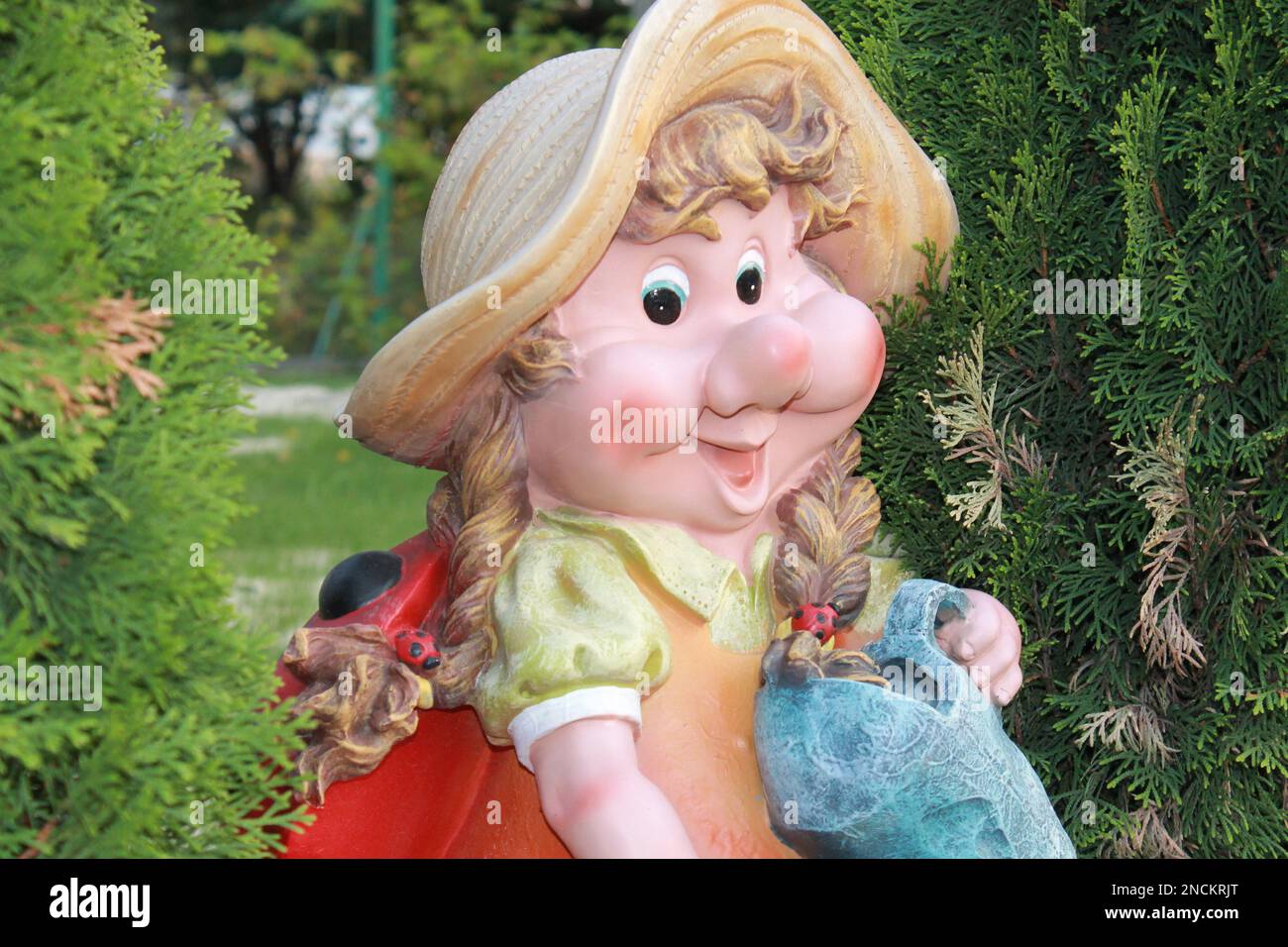 La figure de jardin est une femme naine proche entre les arbres verts, le gnome a un grand sourire Banque D'Images