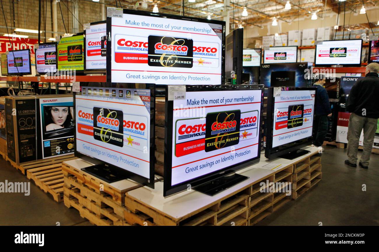 FILE - In this file photo taken March 3, 2010, people look at wide screen televisions at a Costco store in Mountain View, Calif. If you're in the market for a new flat-panel TV, it's a good time to buy. TV prices usually drop from year to year, and the decline will be sharp this 2010 holiday season thanks to a supply glut. Consumers have been holding out all year for better deals, leaving lots of unsold televisions on the shelves. (AP Photo/Paul Sakuma, File) Banque D'Images
