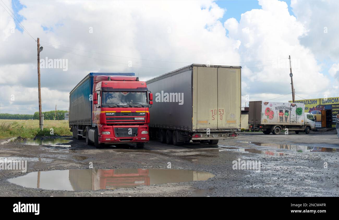 Les gros camions, HOMME du Kazakhstan, se reposent, ont des flaques dans le parking au café sous les nuages blancs d'une journée brillante Banque D'Images
