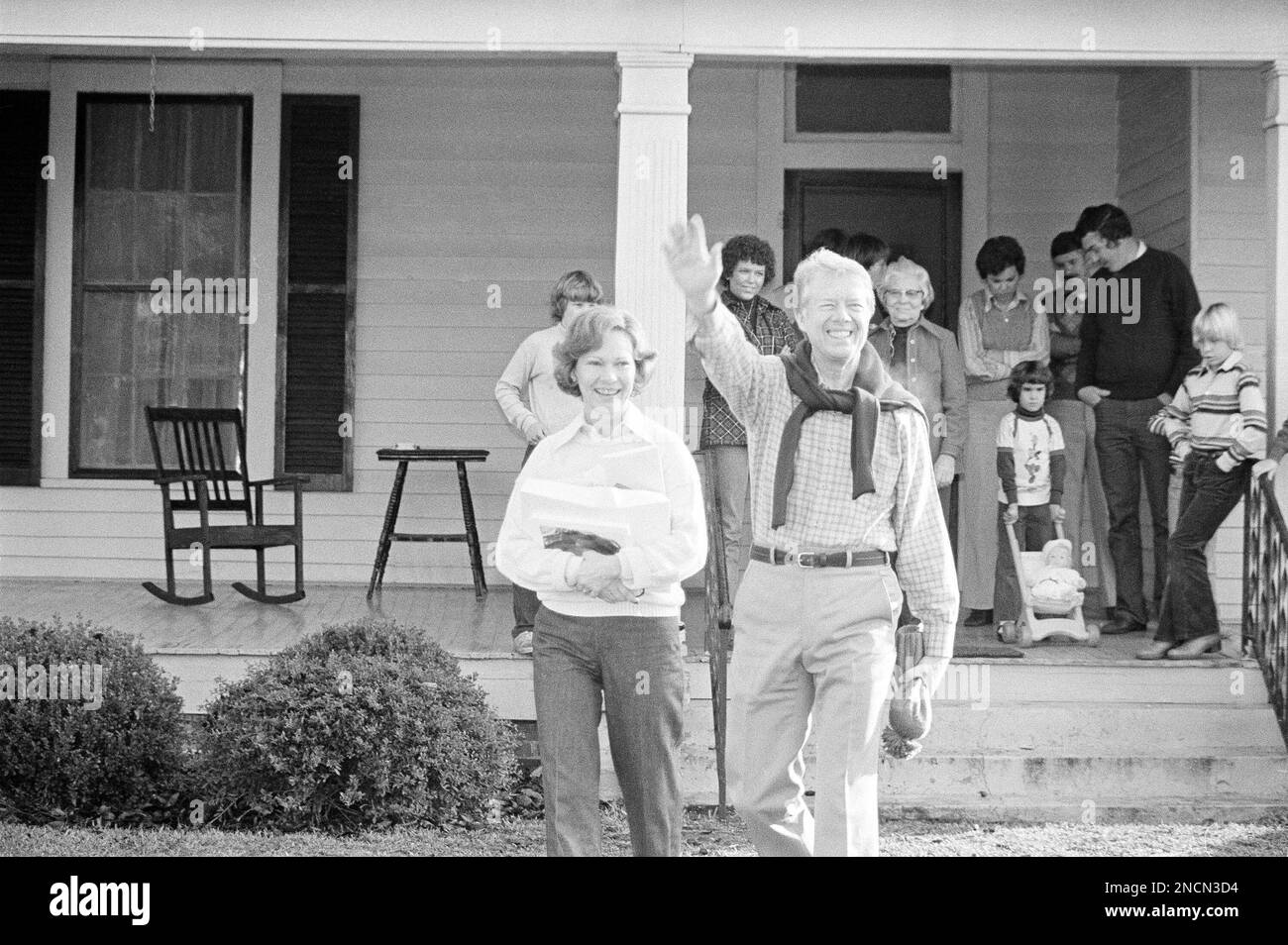 President Jimmy Carter waves to members of the press and spectators as he leaves the home of his mother-in-law in Plains, Georgia on Dec. 25, 1978. Walking with him is first lady Rosalynn Carter and in the background is his mother-in-law, Mrs. Allie Smith (wearing glasses) and members of the family and friends. (AP Photo/Charles Tasnadi) Banque D'Images