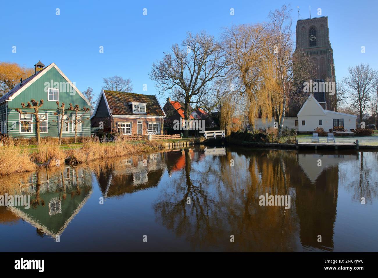 Réflexions de maisons traditionnelles en bois et de l'église de Ransdorp (Kerk van Ransdorp) sur un canal dans le village de Ransdorp, pays-Bas Banque D'Images