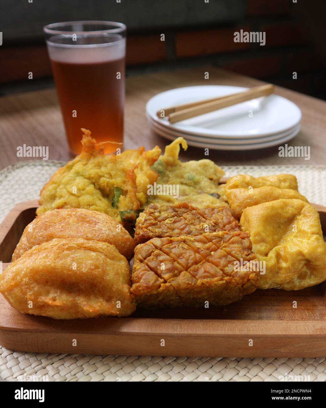 Gros plan de tofu frit, de tempeh frit, de gâteaux de pommes de terre frits et de beignets de maïs sur un plateau en bois Banque D'Images