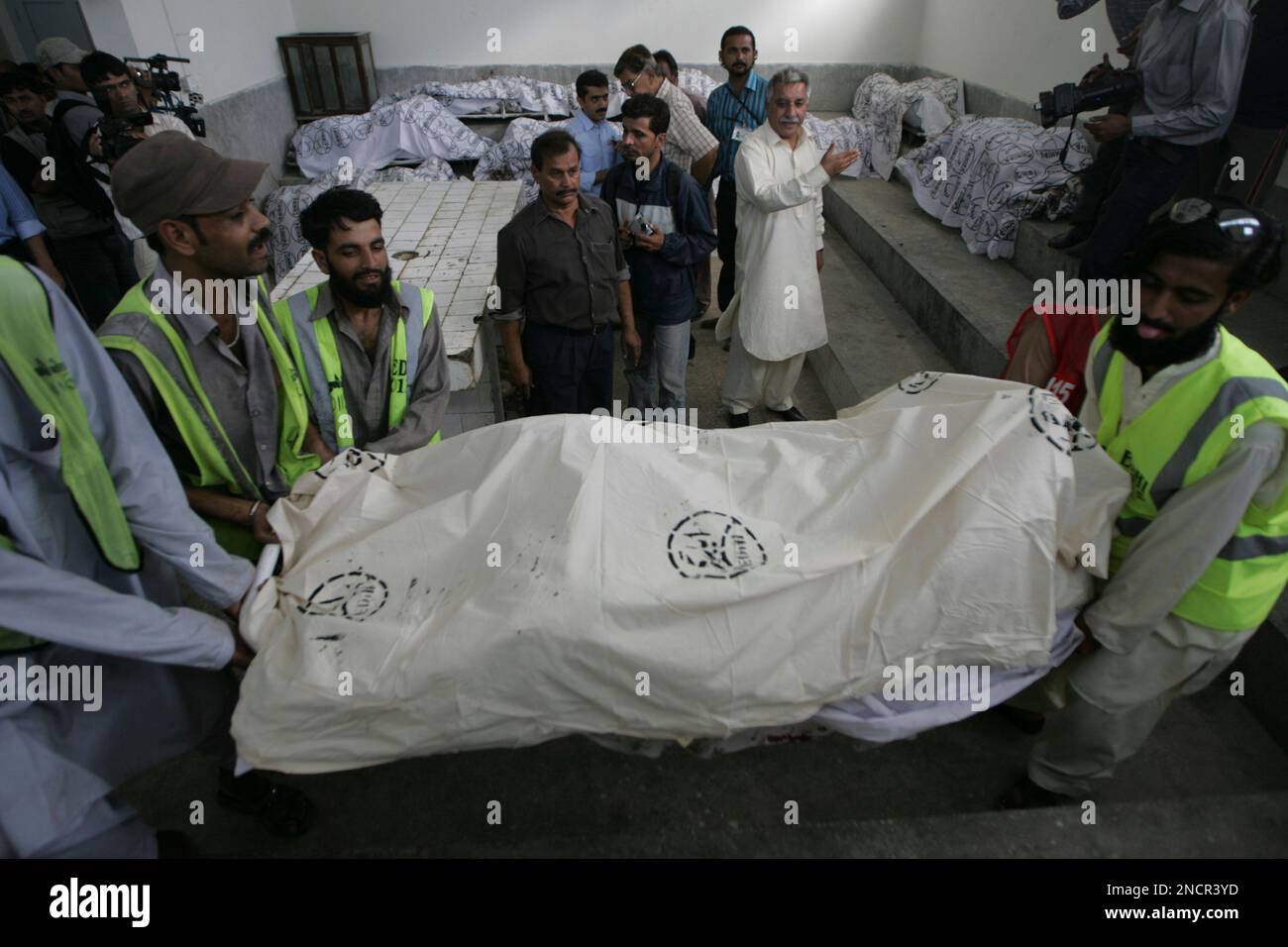 Pakistani volunteers carry a dead body of a plane crash victim at a mortuary in Karachi, Pakistan Friday, Nov. 5, 2010. A small, private plane chartered to an oil company crashed near the airport in Pakistan's largest city Friday after the pilot warned of engine trouble, killing all 21 people on board, officials said. (AP Photo/Fareed Khan) Banque D'Images