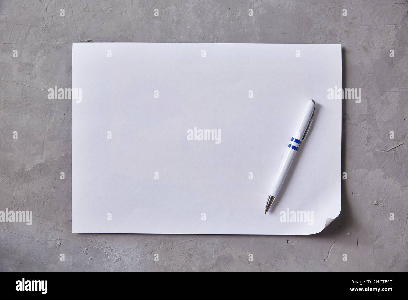 Feuille de papier blanc avec stylo à bille sur fond gris. Copier l'espace Banque D'Images