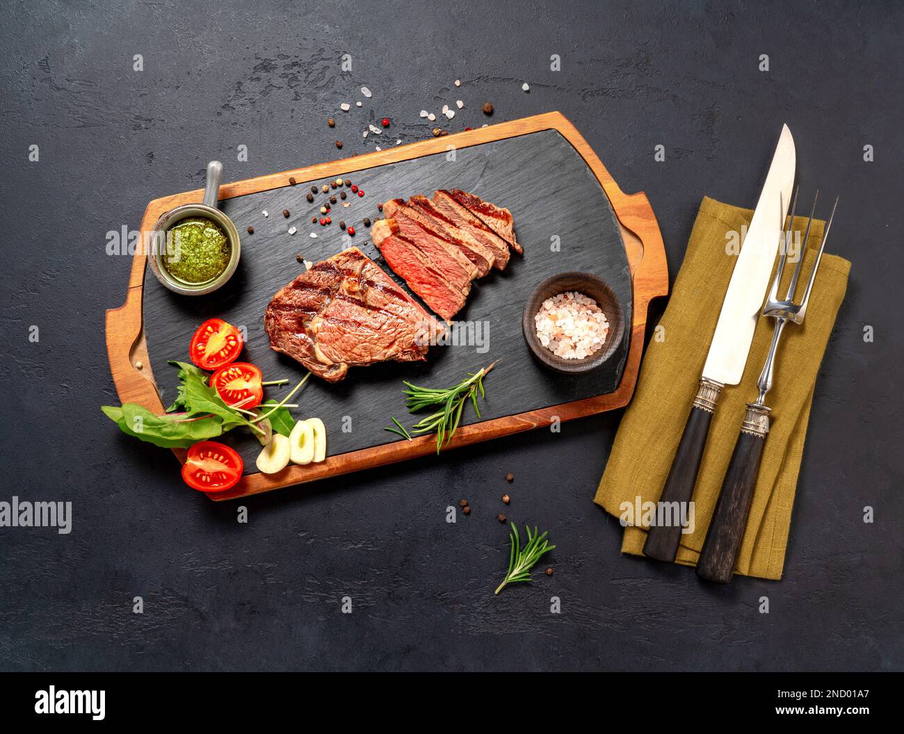 Steak de bœuf à la ribeye grillé, sauce chimichurri, herbes et épices sur une table sombre. Steak en tranches sur le tableau noir pour le steak Banque D'Images