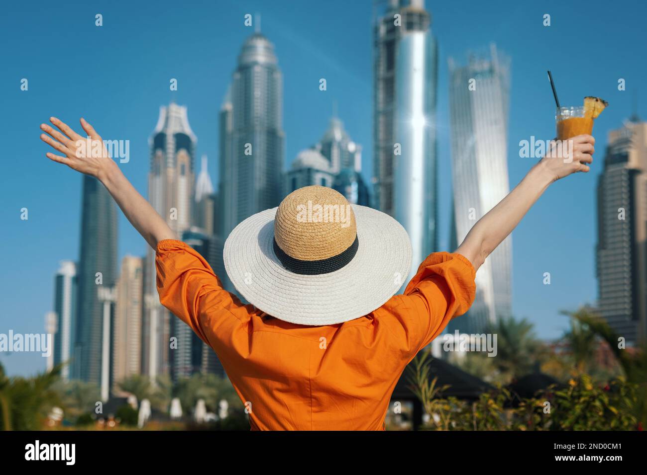 Vacances aux Émirats arabes Unis. Femme debout avec les mains soulevées contre les gratte-ciels de la ville de Dubaï Banque D'Images