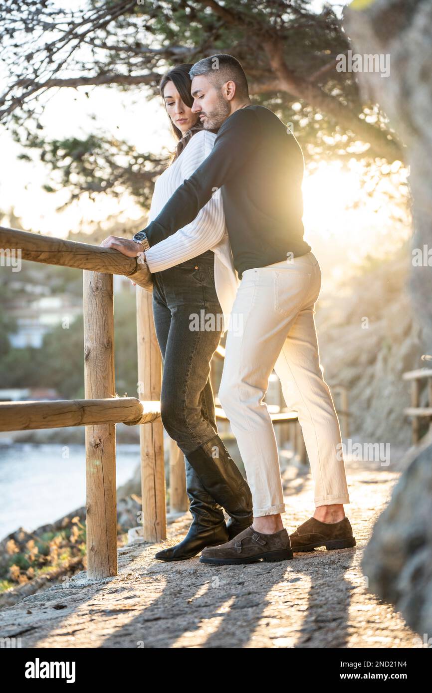 Un couple amoureux dans un sentier près de la plage avec le coucher de soleil sur le fond Banque D'Images