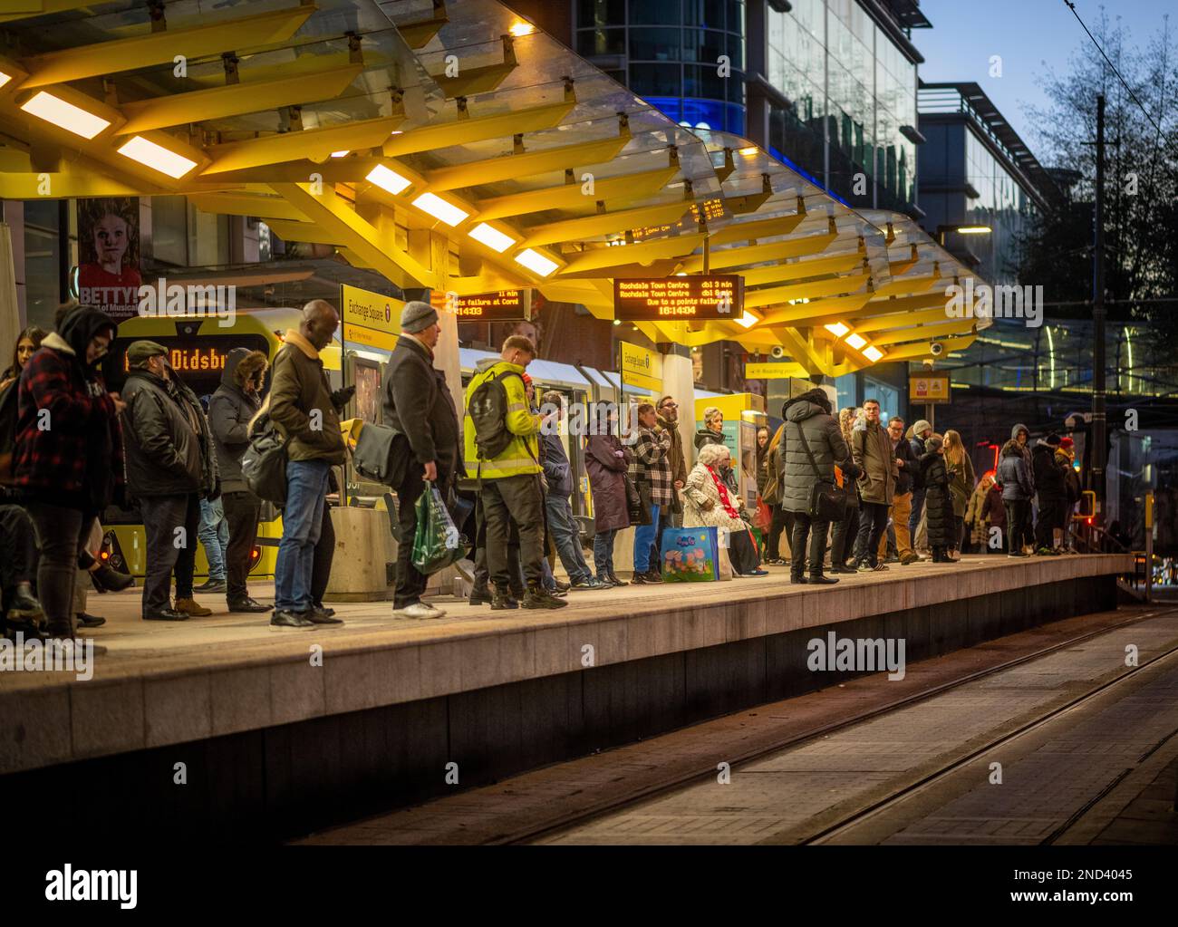 Les passagers qui attendent le tramway Exchange Square s'arrêtent au crépuscule à Manchester. Banque D'Images