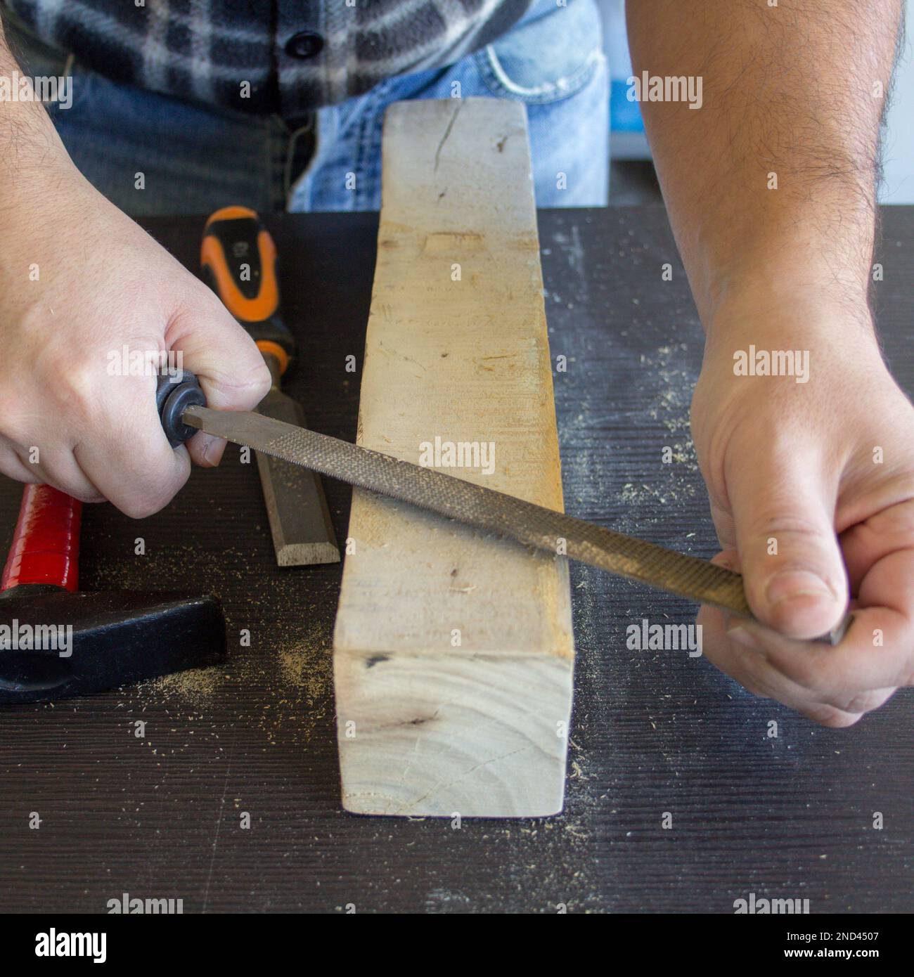 Image des mains d'un artisan charpentier qui lisse un morceau de bois avec une batte. Classement et nettoyage du bois. Banque D'Images Image des mains d'un artisan charpentier qui lisse un morceau de bois avec une batte. Classement et nettoyage du bois. Banque D'Images