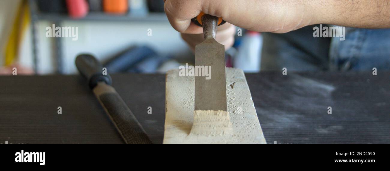 Image des mains d'un artisan manuel tenant un marteau et un burin de charpentier tout en faisant du travail et en sculptant du bois. Travail de bricolage en laboratoire. Banque D'Images