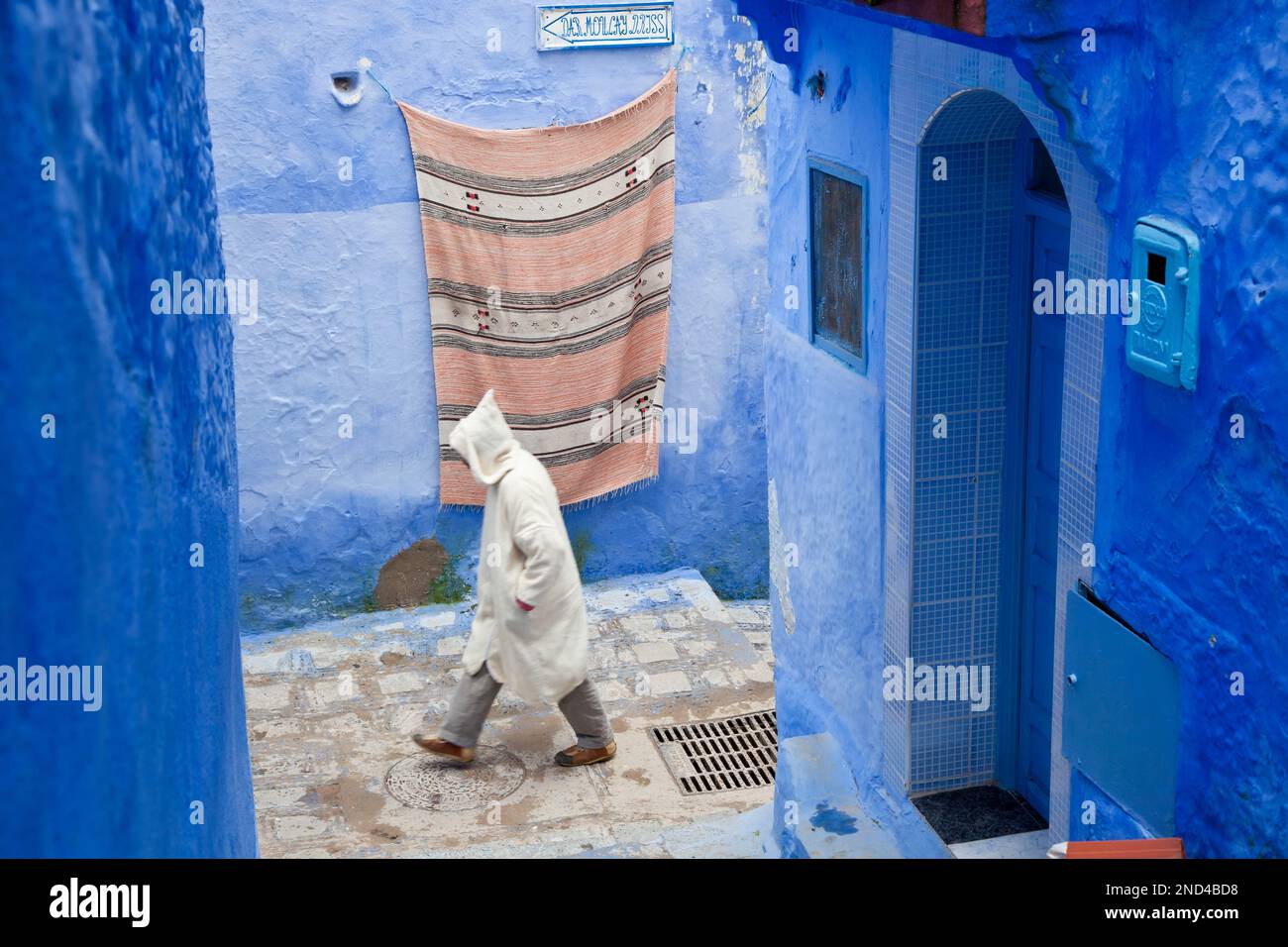 Homme marchant sur la rue portant une djellaba, Chefchaouen, Maroc Banque D'Images
