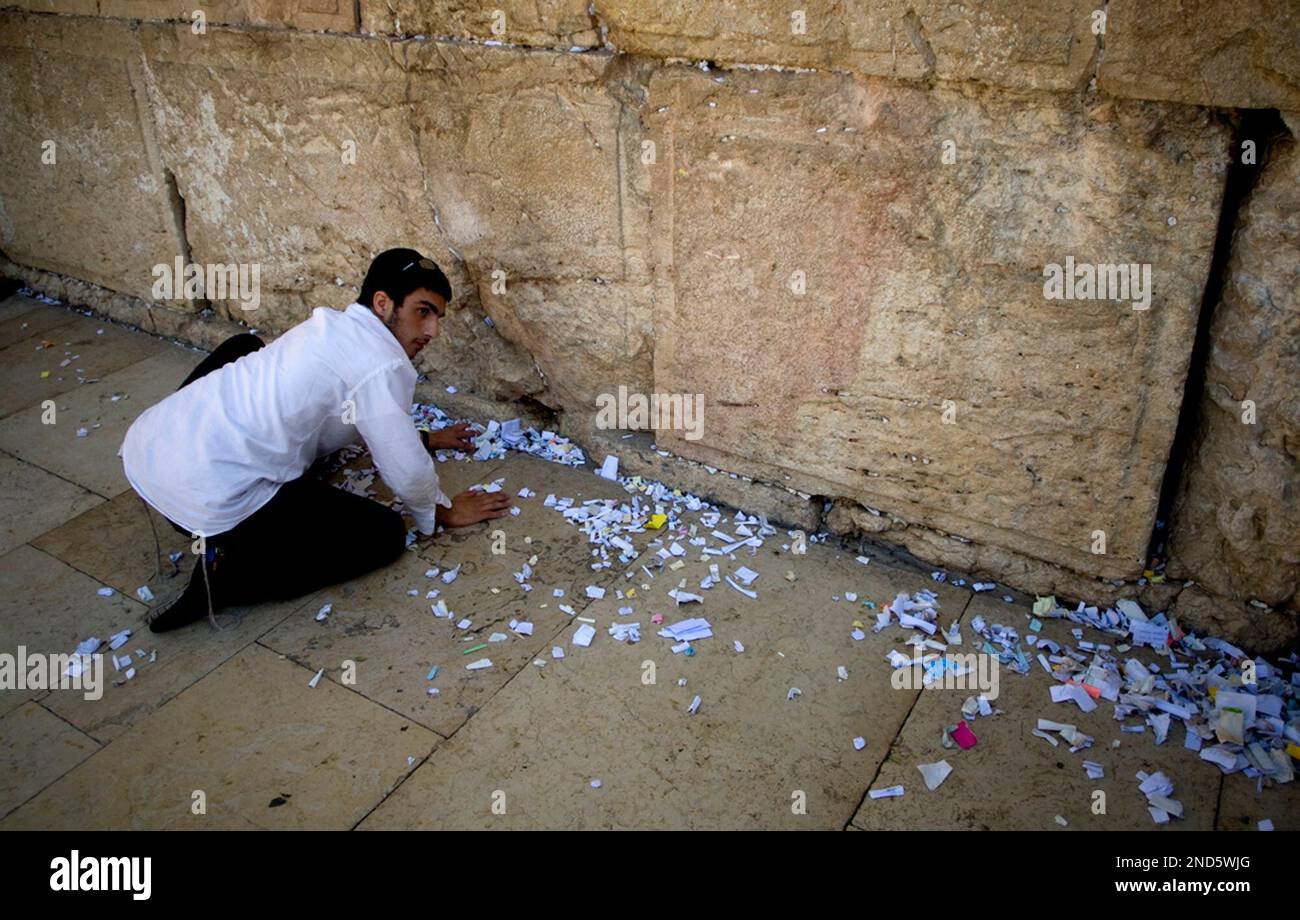 A worker removes prayer notes left by visitors from between the stones of the Western Wall, the holiest place jews can pray, in Jerusalem's Old City, Sunday, Sept. 5, 2010. The notes are buried in a nearby cemetery according to Jewish tradition. People of all faiths slip notes between the stones in the belief that god will answer their prayers. (AP Photo/Sebastian Scheiner) Banque D'Images