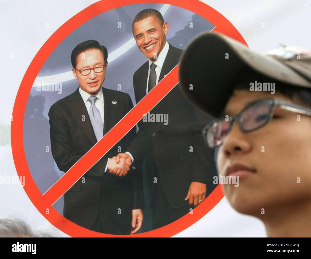 A South Korea protester stands by a defaced picture of South Korean President Lee Myung-bak, left, and U.S. President Barack Obama during a rally opposing the South Korean government's planned sanctions against Iran in front of the government complex in Seoul, South Korea, Tuesday, Aug. 31, 2010. South Korea will soon announce details of its planned sanctions against Iran to comply with a relevant U.N. resolution. (AP Photo/Ahn Young-joon) Banque D'Images