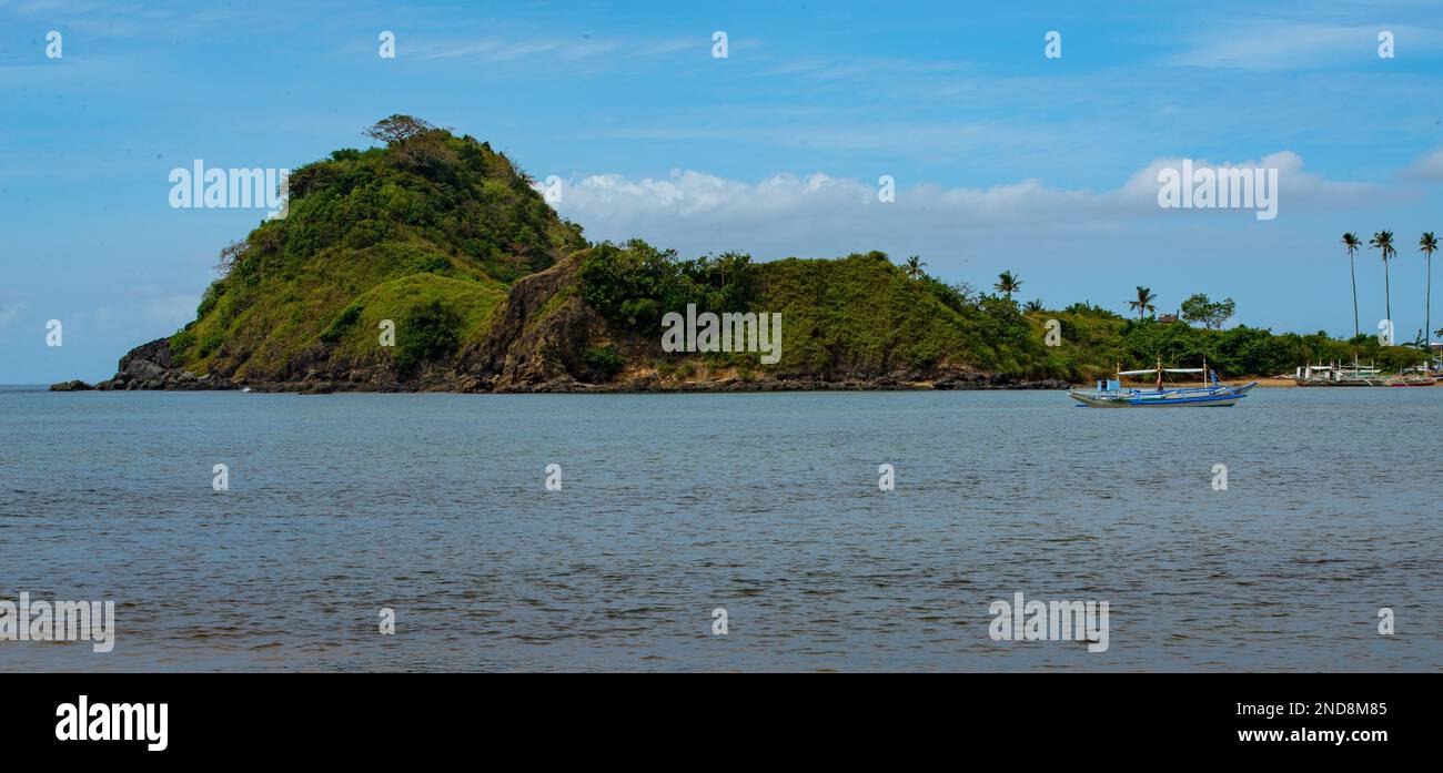 Cette photo capture l'essence des Philippines, avec un bateau traditionnel en bois qui navigue sur des eaux turquoise cristallines, entouré d'un vert luxuriant Banque D'Images