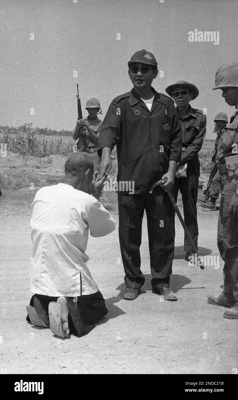 A villager kneels in respect as Cambodian President Lon Nol makes an inspection tour of villages near the besieged capital of Phnom Penh on Sunday, March 16, 1975. Lon Nol carries a cane. (AP Photo) Banque D'Images