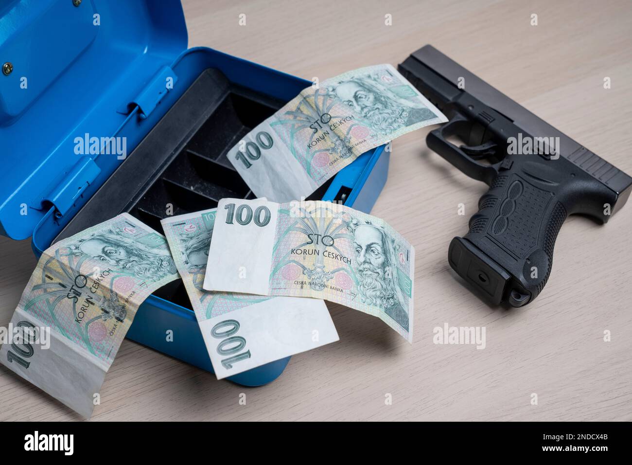 Un wad de 100 korun tchèque en espèces et un pistolet noir avec un coffre-fort. Banque D'Images